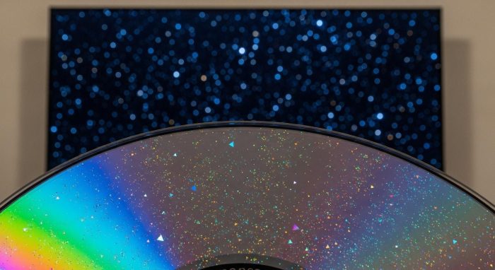 4Kブルーレイディスクの表面と背景に映る有機ELテレビの漆黒の宇宙映像